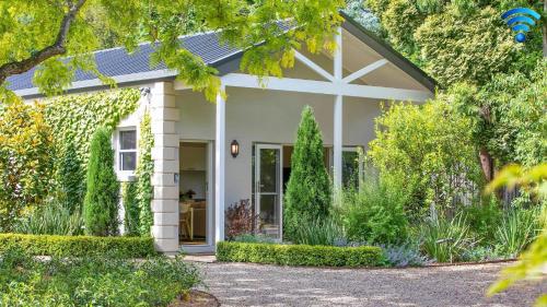a small white house with a garden at Banyula Annex in Burradoo