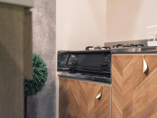 a kitchen with a black stove and wooden cabinets at Tsubame INN Nipponbashi in Osaka