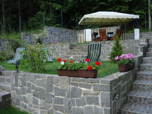 a retaining wall with two chairs and flowers and an umbrella at Penzión Zlatý Jeleň in Košice