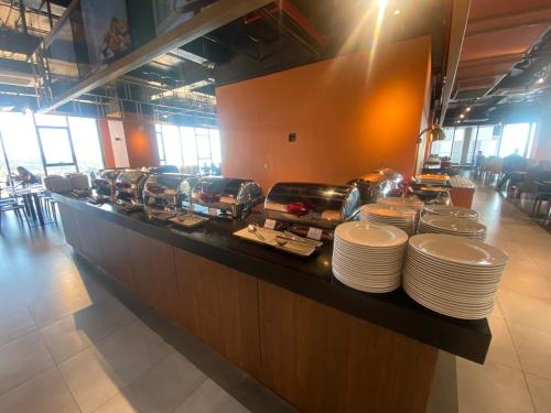 a buffet line with plates on a counter in a restaurant at APEC Mandala Cham Bay Mũi Né in Ấp Thiẹn Ái