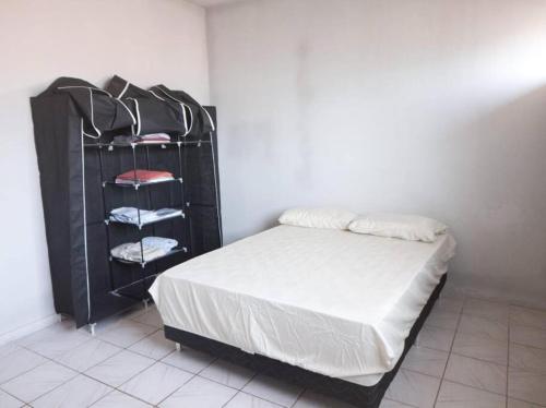 a bedroom with a bed and a black rack with towels at Apto com Estac Gratis e Conforto in Paragominas