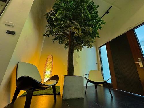 two chairs and a table and a tree in a room at 安平胡桃民宿-公園景觀泡腳池-免費停車-專屬電梯-烤肉租借 in Tainan
