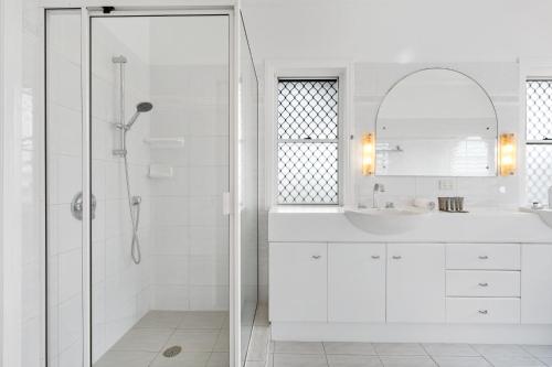 a white bathroom with a shower and a sink at Peaceful Family Home: 4-Bed Pool Alfresco Dining in Albany Creek