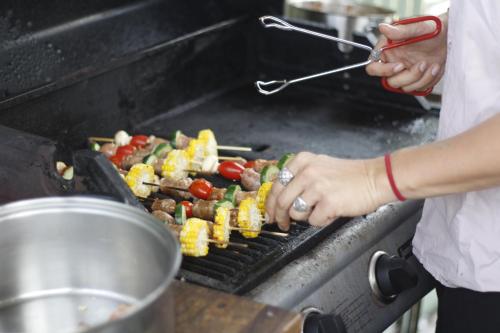 a person is cooking food on a grill at Boardrider Backpackers and Budget Motel in Sydney