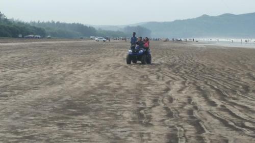a group of people riding a quad bike on the beach at Tendulkar Beach Resort in Diveagar