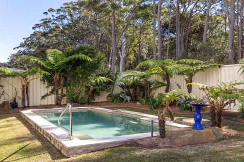 a swimming pool in a yard with trees and a fence at The Atrium by Experience Jervis Bay in St Georges Basin