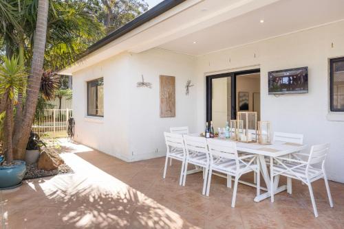 a white dining room with a white table and chairs at The Atrium by Experience Jervis Bay in St Georges Basin