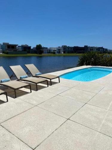 two lounge chairs and a swimming pool next to the water at Casa de Luxo no Condomínio Enseada in Xangri-lá