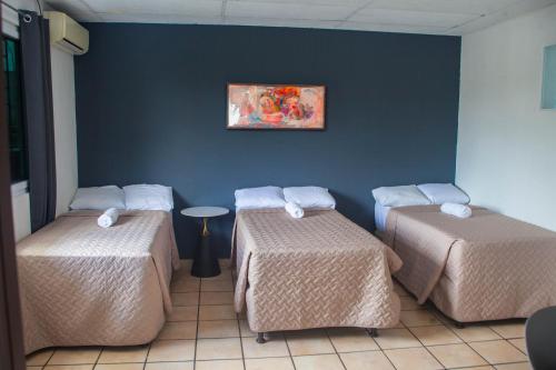 Una habitación con tres camas y un cuadro en la pared. en Hotel Casa Manantiales, en Mexicanos