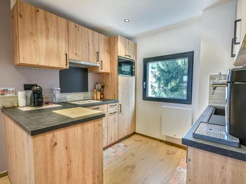 une cuisine avec des armoires en bois et un comptoir dans l'établissement T3 rénové au centre, parking, casier à skis, 4-6 pers - FR-1-685-81, aux Gets