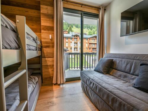 - un salon avec un canapé et des lits superposés dans l'établissement T3 rénové au centre, parking, casier à skis, 4-6 pers - FR-1-685-81, aux Gets