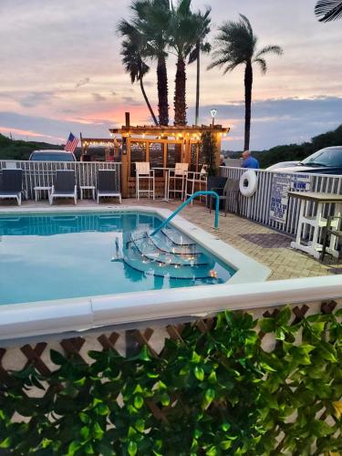 a pool at a resort with a bar and palm trees at Ocean Sands Beach Boutique Inn-1 Acre Private Beach-St Augustine Historic-2 Miles-Shuttle with Downtown Tour-HEATED Salt Water Pool until 420AM-Popcorn-Cookies-New 4k USD Black Beds- 69 Item Breakfast-Eggs-Bacon-Starbucks- Free Laundry- #904-799-SAND in Saint Augustine