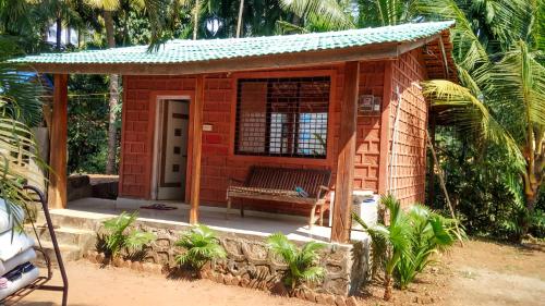 a small red building with a bench in it at Tendulkar Beach Resort in Diveagar