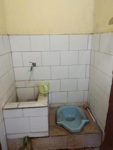 a dirty bathroom with a blue toilet in the floor at Menginap di rumah tenun Astiti in Klungkung