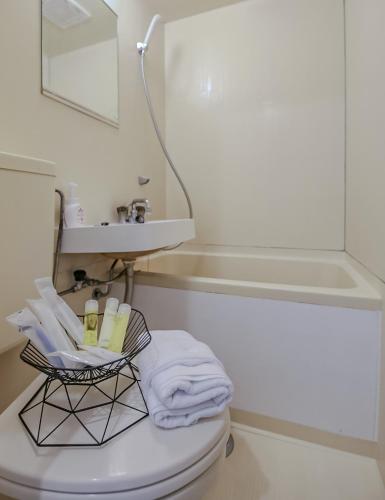 a bathroom with a toilet with a sink and a mirror at ゲストハウスあさひ in Atami