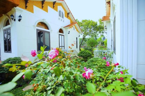 a garden with pink roses in front of a house at Hoa Lu Garden Resort in Ninh Binh