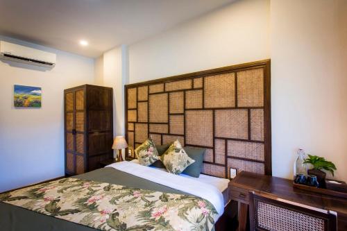 a bedroom with a large bed and a wooden desk at Hoi An Clara House in Hoi An