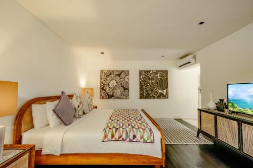 a bedroom with a large bed and a flat screen tv at Martini Suite and Villa in Kerobokan