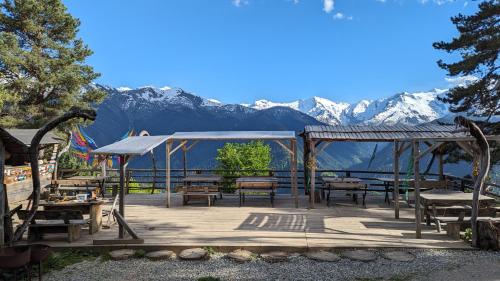 a patio with tables and benches with mountains in the background at Heshkili huts and cabins Svaneti in Keshkili