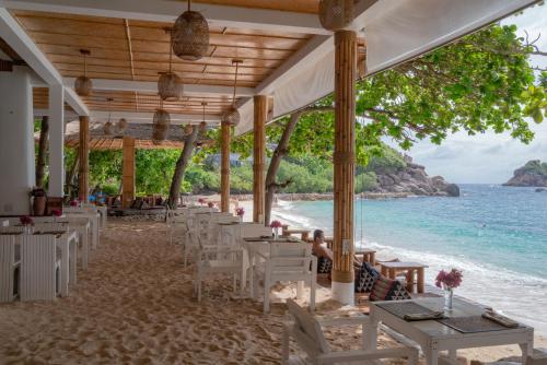 a restaurant on the beach with tables and chairs at Sai Daeng Resort in Koh Tao