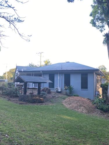 a blue house with a porch and a yard at Koala Cabins Sunshine Coast in Mapleton