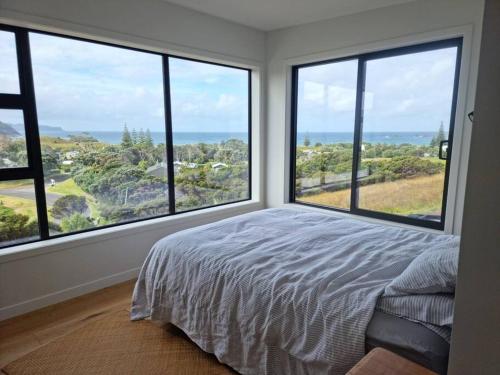a bedroom with large windows and a bed with a view at XSPOT Medlands Beach House - Ocean views - Short stroll to the beach in Medlands