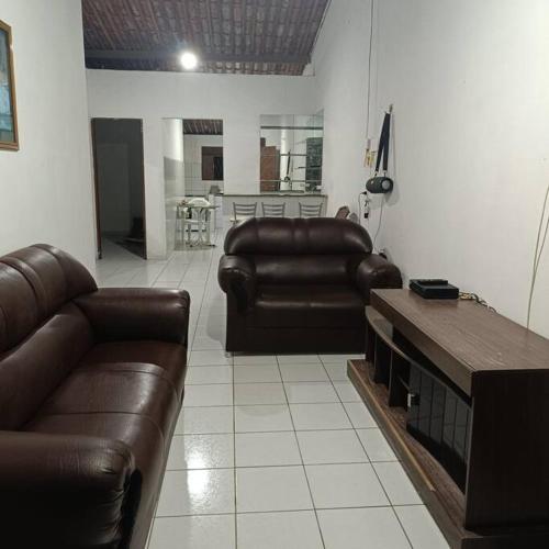 a living room with two leather couches and a table at Casa temporada in Baía Formosa