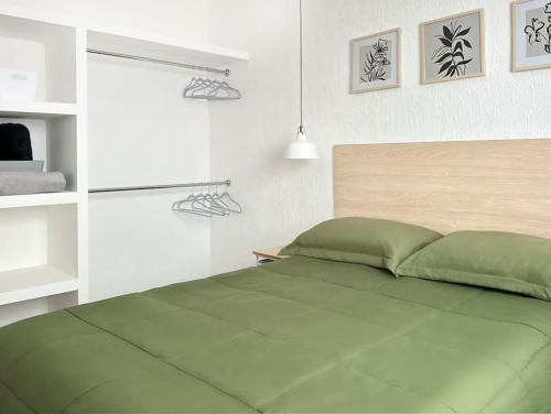 エルモシージョにあるCasa 2 Recámaras con acceso controladoの白い部屋に緑のベッドが備わるベッドルーム1室