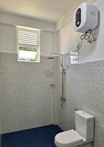 a bathroom with a shower with a toilet and a window at OUNA Bungalow in Ella