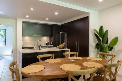 a kitchen with a wooden table and chairs and a kitchen with a sink at Luxury Port Douglas beachside 3 Bedroom Temple Apartment with Private roof top terrace Due to copyright we can't disclose the resort name but google Port Douglas temple and this fantastic 5 star resort will come up in Port Douglas
