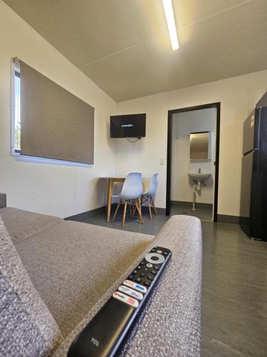 a room with a bed and a tv and chairs at Bundaberg Park Village in Bundaberg