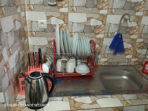 Un fregadero de cocina con un estante para platos y utensilios. en Résidence Meublée Smart 2, en Man