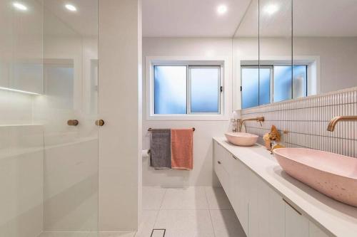 Un baño con lavabo y ducha de cristal. en Luxe Modern Waterfront 4BR Oasis Wifi, BBQ & Pool, en Gold Coast