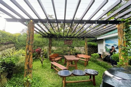 a pergola in a garden with benches and tables at Viewscape Nature Park Tanay powered by Cocotel in Tanay