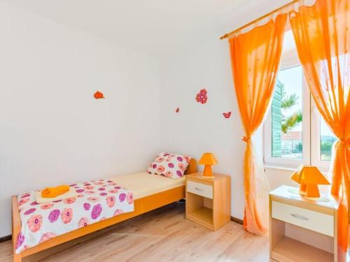 a bedroom with a bed and a window with orange curtains at Apartment Magdalena - Three Bedroom Apartment in Nerežišća