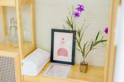 a table with a picture and a vase with purple flowers at Antus Homestay in Quang Ninh