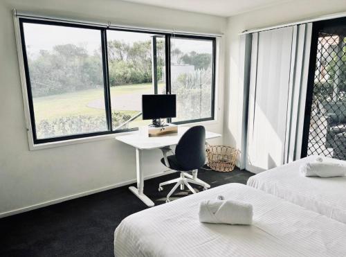 a bedroom with two beds and a desk with a computer at 21 Whales Parade in Diamond Beach