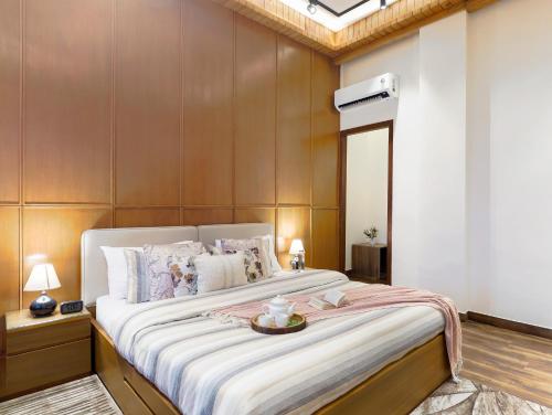 a bedroom with a large bed with a wooden wall at ELIVAAS 4 BHK with Balcony & Terrace - Antarmann Casa Nova in Bhīm Tāl