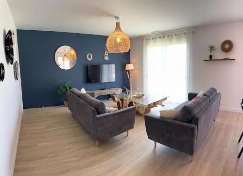 a living room with two couches and a table at Maison de vacances in Le Teich