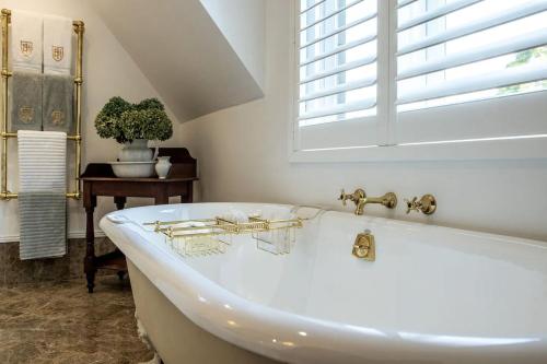 a white bath tub in a bathroom with a window at Ben Huon Manor, Robertson, Southern Highlands, NSW in Robertson