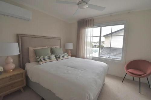 a white bedroom with a large bed and a window at Luxury Mooloolaba Waterfront Retreat in Mooloolaba
