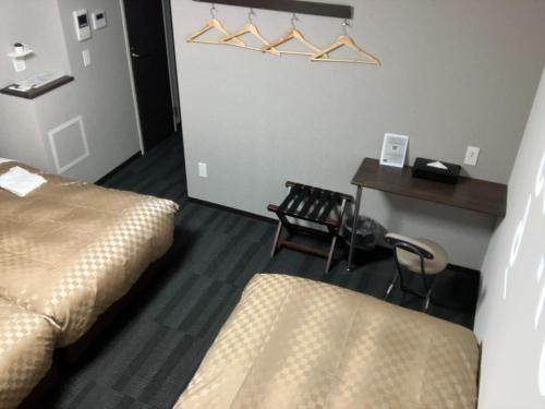 a room with two beds and a table and a desk at MERBABU STAY OSAKA in Osaka