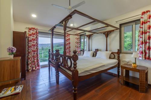 a bedroom with a canopy bed and a large window at SaffronStays Horizon 360, A Short Walk From Venna Lake and Mahabaleshwar Market in Mahabaleshwar