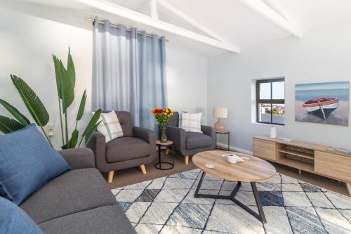 un soggiorno con un divano, sedie e un tavolo di The Sandcastle Guesthouse - Melkbosstrand a Melkbosstrand
