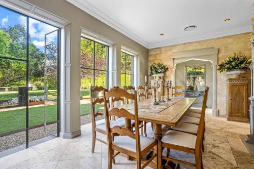 a dining room with a table and chairs and large windows at Ben Huon Manor, Robertson, Southern Highlands, NSW in Robertson