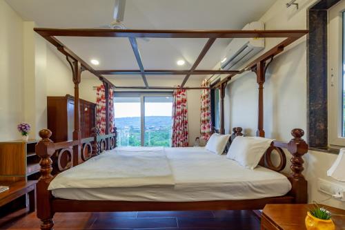 a bedroom with a canopy bed with a window at SaffronStays Horizon 360, A Short Walk From Venna Lake and Mahabaleshwar Market in Mahabaleshwar