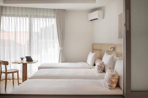 a hotel room with two beds and a window at U Hua Hin in Cha Am