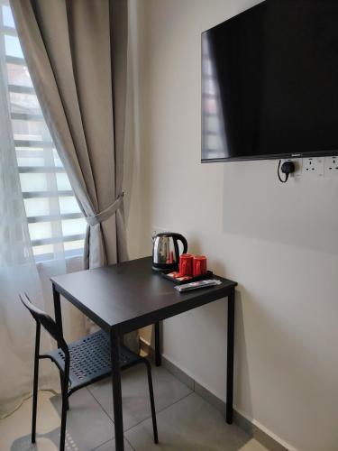 a black table with a tea kettle on it next to a window at Austin Melaka in Kampong Sungai Putat