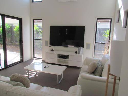 a living room with white furniture and a flat screen tv at Casuarina Escape by Kingscliff Accommodation in Casuarina