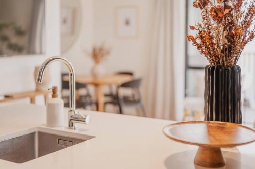 un comptoir de cuisine avec un évier et un vase avec des fleurs dans l'établissement Chic and Contemporary Living at Cambridge Terrace, à Christchurch